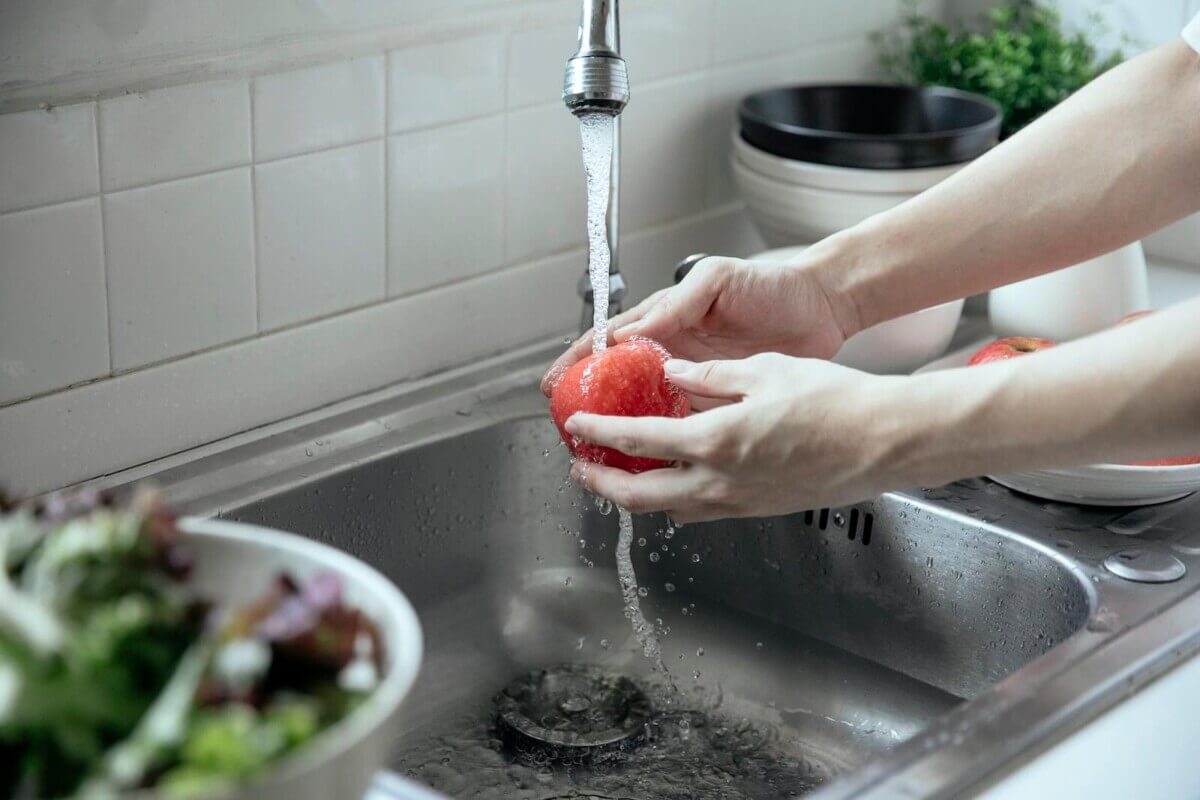Person washing produce in the sink