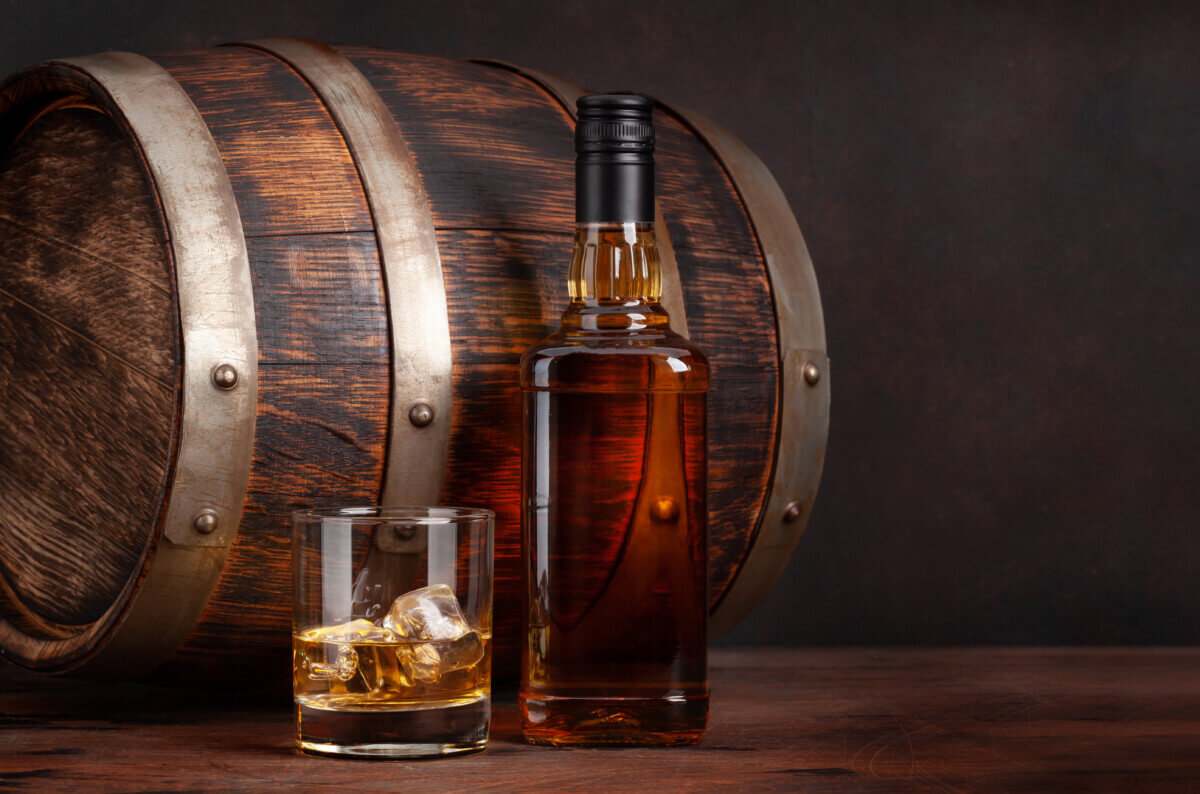 A bottle of rum next to a barrel