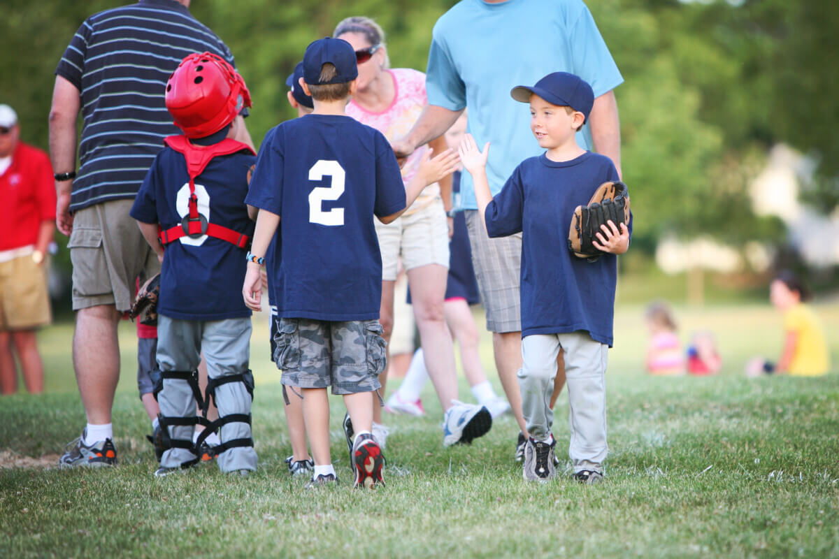 Children high-fiving after little league baseball game