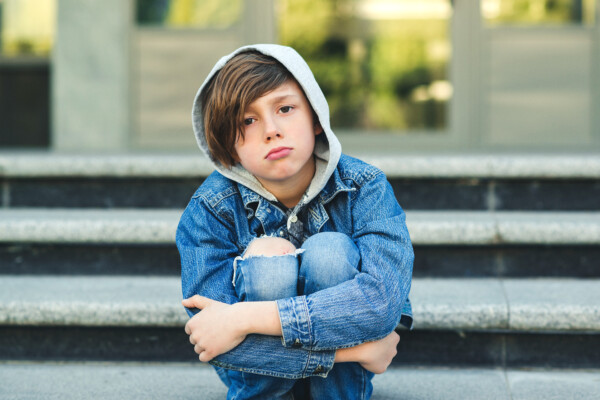 Sad teen child sitting alone on steps