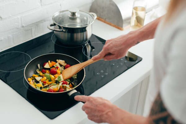 Person cooking vegetables in frying pan