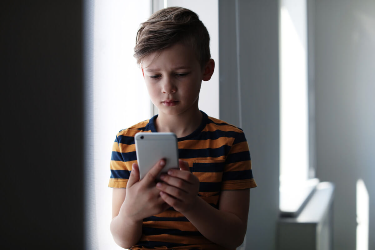 Sad young boy with smartphone