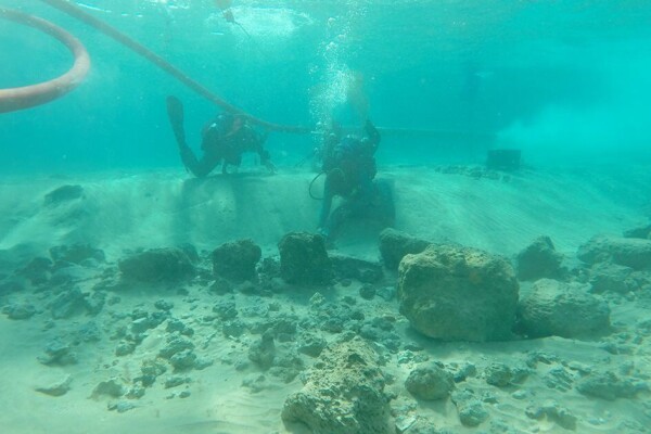 Divers on a research team examine architectural remains at the underwater village of Habonim North, off Israel's Carmel Coast.