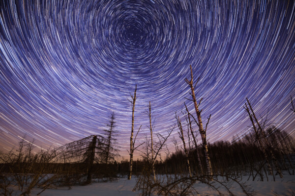 Winter starry night landscape with circle star trails