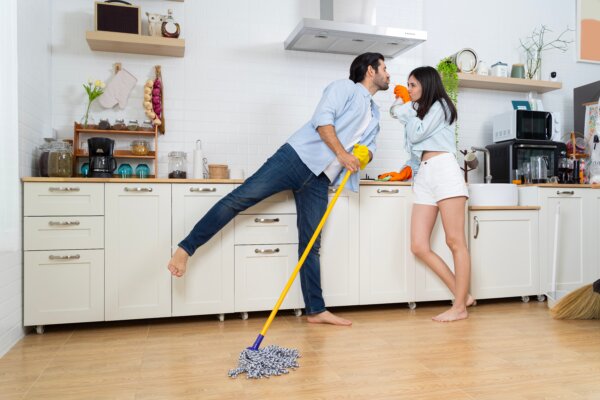 Young happy couple having fun while doing cleaning kitchen.