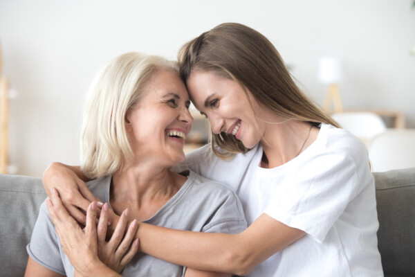 older mature mother and grown millennial daughter laughing