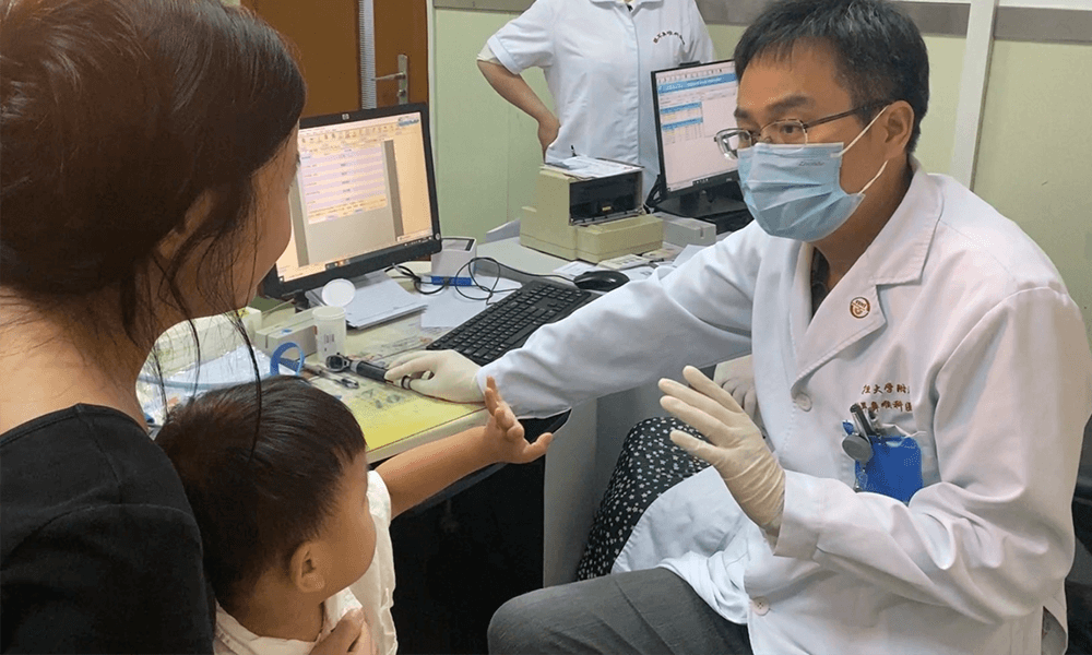Dr. Yilai Shu communicates with a young patient at the Eye & ENT Hospital of Fudan University.